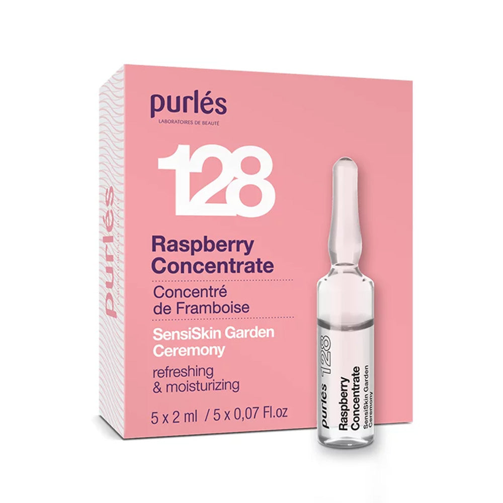 Eine Schachtel mit Purlés Sensi Skin Garden Ceremony 128 Raspberry Concentrate, mit einer kleinen transparenten Ampulle auf der Vorderseite. Die rosa-weiße Verpackung zeigt Produktdetails auf Englisch und Französisch und hebt die erfrischenden und feuchtigkeitsspendenden Eigenschaften hervor.