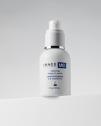 Eine 30-ml-Flasche Image Skincare IMAGE MD Restoring Power C Serum mit einer Pumpe steht vor einem hellgrauen Hintergrund. Das Etikett zeigt blauen und schwarzen Text sowie ein blaues Bechersymbol.