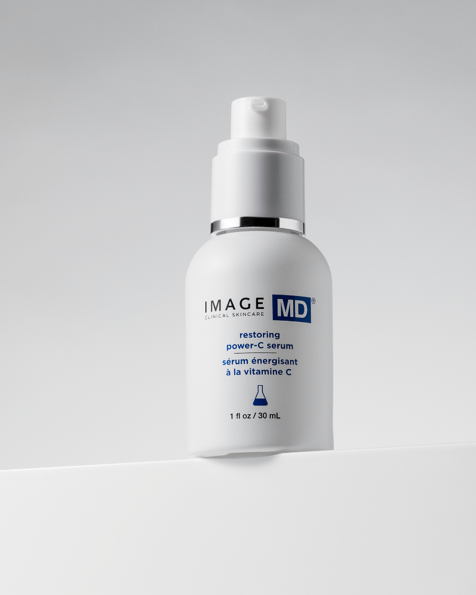Eine 30-ml-Flasche Image Skincare IMAGE MD Restoring Power C Serum mit einer Pumpe steht vor einem hellgrauen Hintergrund. Das Etikett zeigt blauen und schwarzen Text sowie ein blaues Bechersymbol.