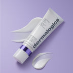 Eine Tube „Dermalogica – Stabilizing Repair Serum“ mit violetter Verschlusskappe liegt auf einem lavendelfarbenen Untergrund, umgeben von drei weißen Serumflecken – ideal für alle, die ein „Serum für empfindliche Haut“ suchen, um „die Hautbarriere zu stärken“ und Linderung bei Ekzemen zu verschaffen.