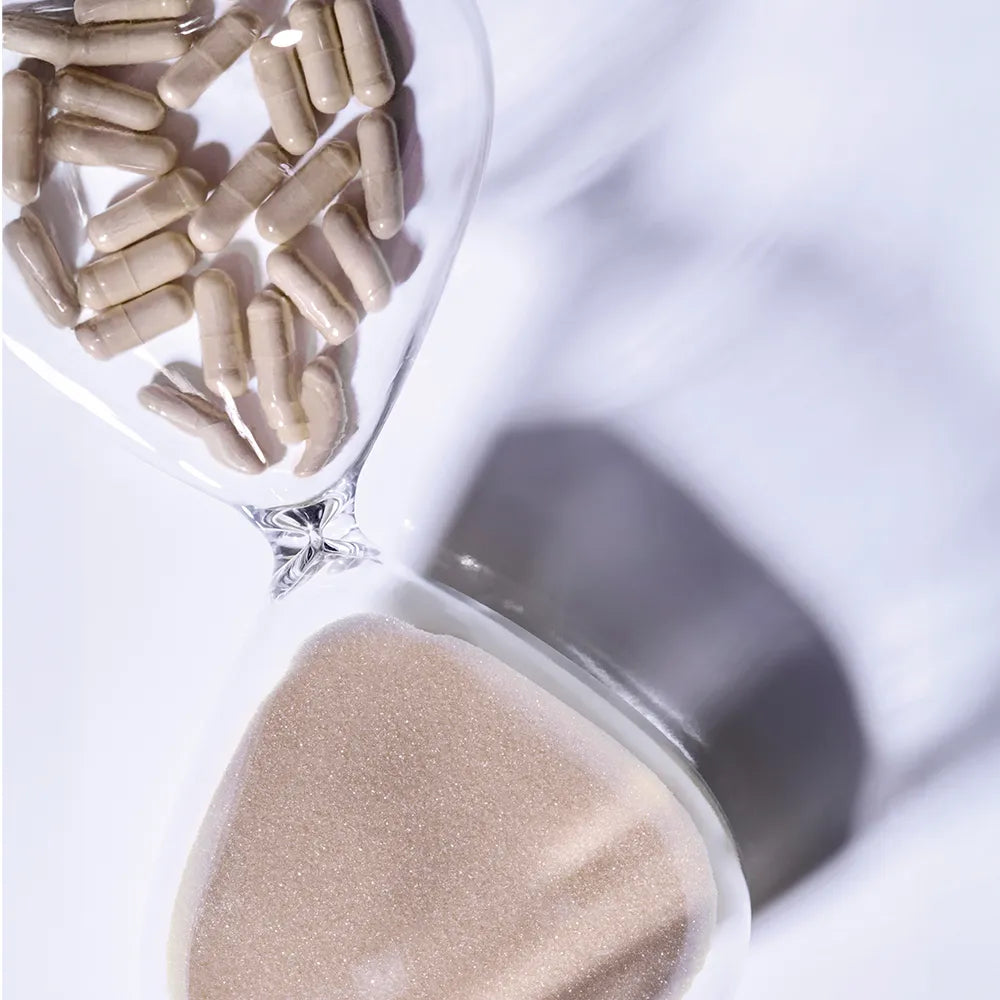 Nahaufnahme einer Sanduhr mit braunen Kapseln im oberen Teil und Sand im unteren Teil, die Zeit und Gesundheit symbolisieren, mit LPG - FAT-BURNING CONCENTRATE von LPG.